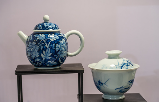 A tea ceremony with Puer tea in Lijiang, China. A female hand lifts the lid from a blue and white teapot.