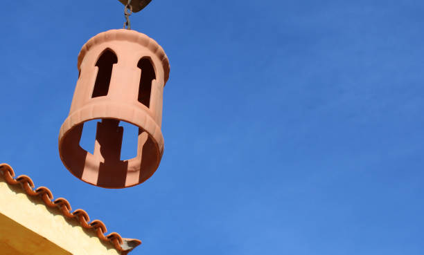 terracotta lantern in front of a roof cutout. next to it is a blue sky with a copy space for writing in for holiday greetings from spain. the spanish roof is yellow with terracotta roof tiles on the corner of the house