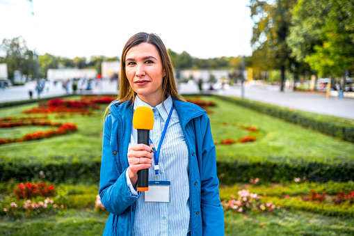 Cheerful female news reporter in live broadcasting in the city