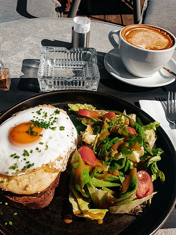 Breakfast is served on a table in a street cafe on a sunny morning. A cup of coffee and a vegetable salad with an egg. Still life photo.