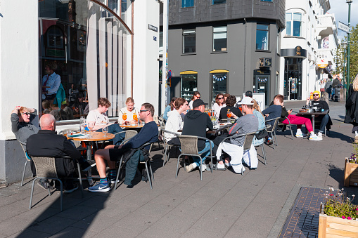 REYKJAVIK, ICELAND - 28 JUNE 2022:  People sit near coffee shop and drink coffee on Reykjavík street. Iceland