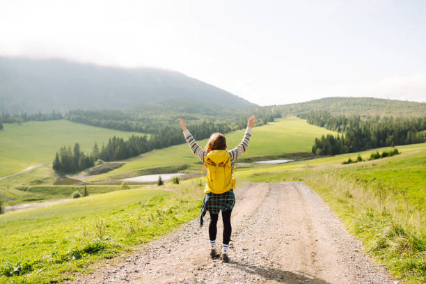 istock Young Woman walking on through green grass valley on background big mountains. 2009826295