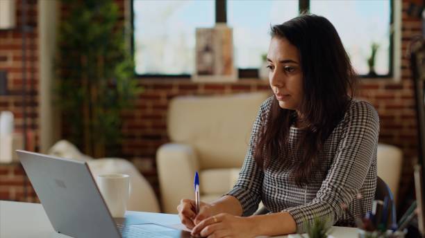 istock Remote employee at desk, transcribing data from laptop to notepad 2009836239