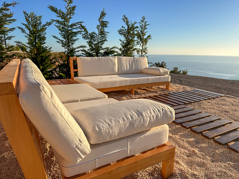 Relaxation area on a cliff with white sofas and panoramic sea views.