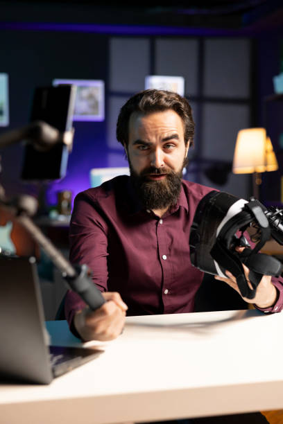 istock Man presenting VR goggles, filming video with smartphone on selfie stick 2009879131