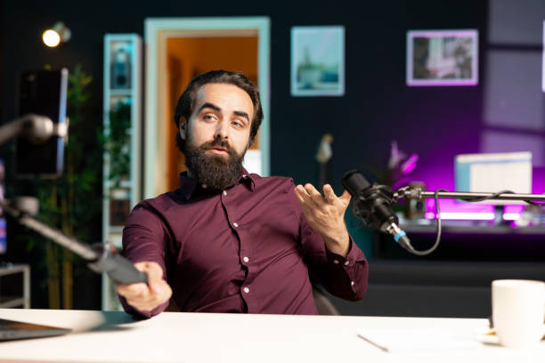 istock Man using phone camera and professional microphone to record vlog in apartment 2009880730