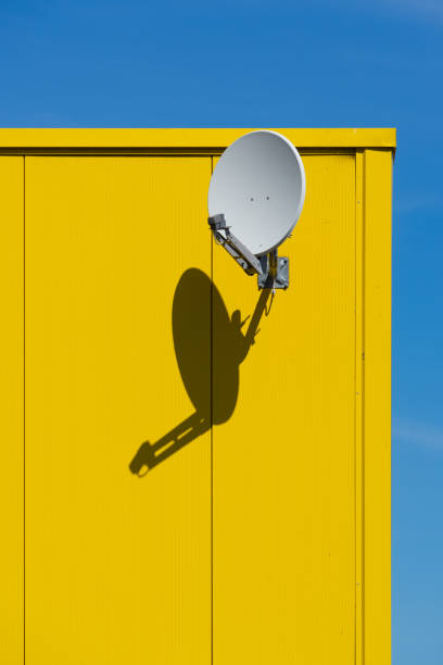 Germany, Berlin, Jane 17, 2022 - Satellite dish on yellow building against clear sky, Berlin central