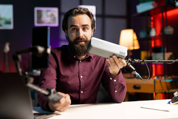 istock Influencer showing music playing device, filming with phone on selfie stick 2009903394