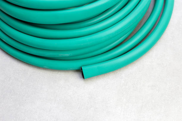 Green garden hose on cement floor background.