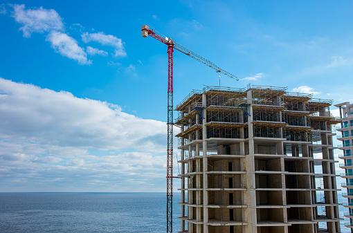 Work in progress, building tall luxury tower building by the sea. Construction industry.