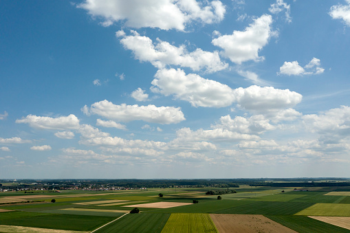 Beautiful spring landscape with green fields and blue sky with clouds, visible from a bird's eye view.