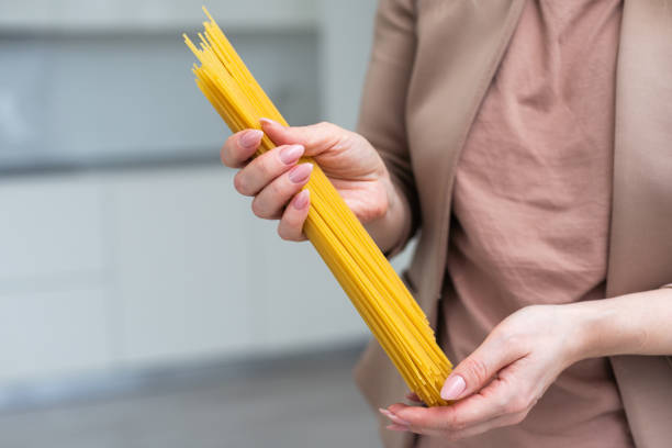 close up human hand holding fresh spaghetti pasta italian dish for cooking isolated on white background. - breaking pencil impatient women photos et images de collection