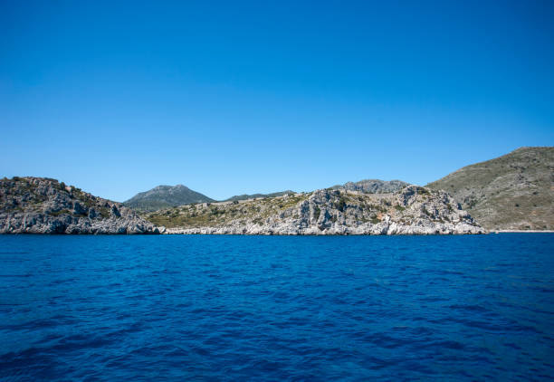 serene sea waters touch the rugged shores where old stone ruins reminisce a bygone era, under the clear sky