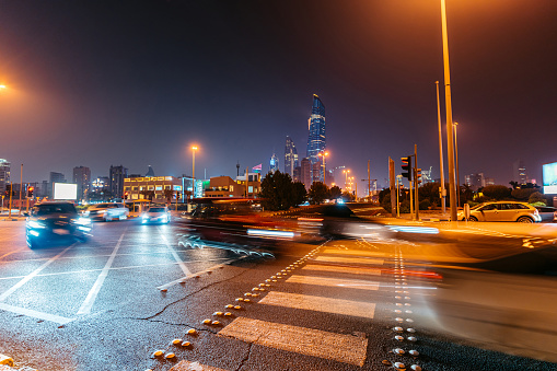 Crosswalk scene with blurred motion traffic in Kuwait City at night.