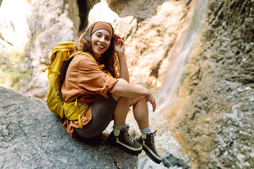 Travel young woman walking in canyon with moss on rocks after hiking. Traveling through scenic spots. Travel, trekking. Nature concept.