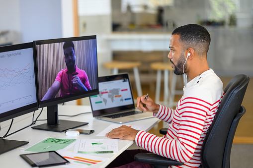 Business people taking with colleague during conference call on computer while sitting in modern office.