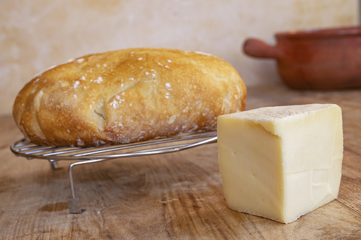 wedge of artisanal caciotta cheese near a loaf of homemade bread