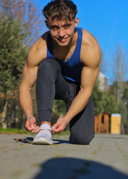 istock Caucasian man smiling tying his sneakers kneeling 2010031028