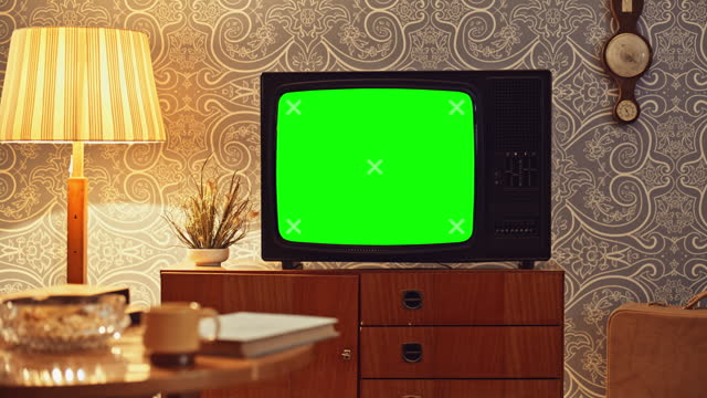 LD An old TV set on the cupboard in the living room with a green screen