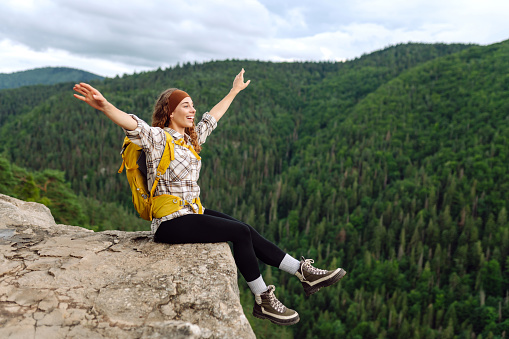 Young woman with backpack on mountain peak enjoying nature. Hiking.Travel and tourism. Active lifestyle.