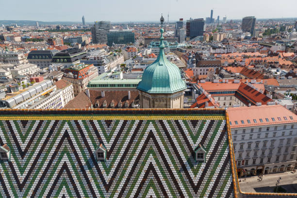 The roof tiles pattern and a tower of the Saint Stephen Cathedral and the historical buildings of center Vienna in Austria