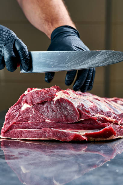 istock Butcher cuts a fresh piece of beef on the table 2010094438