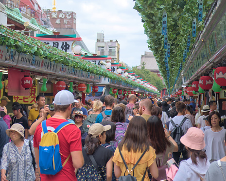 A street full of tourists buying souvenirs in Nakamise Shopping Street near Sensoji temple, Asakusa Tokyo. Photographed in summer 2019.