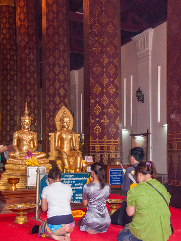 Ayutthaya, Thailand - December 24, 2009: local people pray in front of the golden buddha in the temple in Ayutthaya.