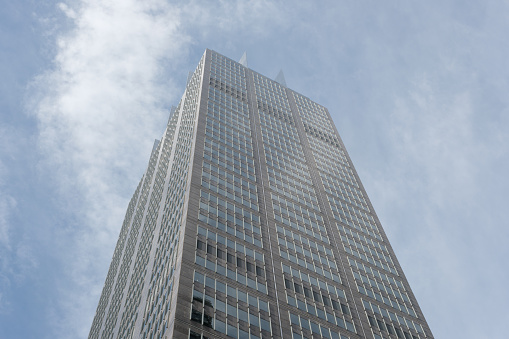 Close-up on a tall city office building with cloudy sky beyond.