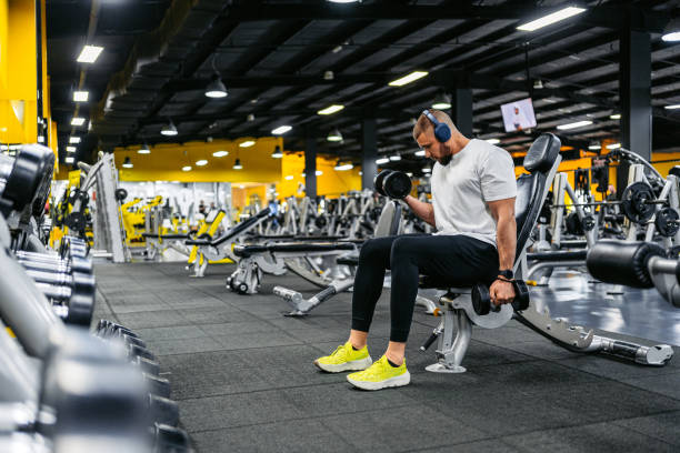 istock Young Man Training With Dumbbells While Listening To Music In The Gym 2010128005