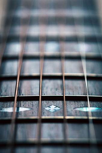 Extreme close up view of steel strings and fretboard of an acoustic guitar.