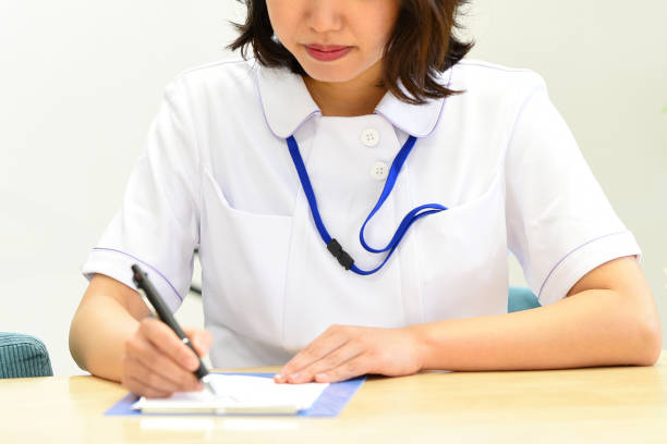 白衣を着てメモを書くアジアの若い女性医療従事者 - 病院 診断書 ストックフォトと画像