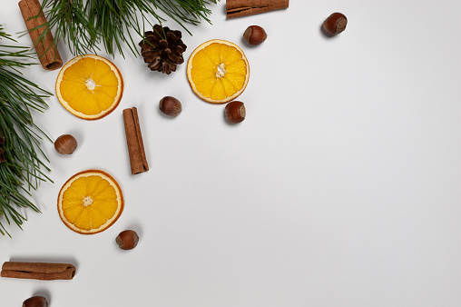 Christmas composition, dried orange slices, fir tree branches, cinnamon sticks, pine cones, hazelnuts on white background. Christmas, New Year, winter concept. Top view, flat lay, copy space.