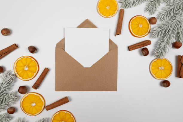istock Christmas composition, dried orange slices, fir tree branches, cinnamon sticks, hazelnuts on white background. Kraft envelope, white card. 2010150702