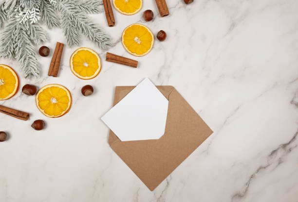 Christmas composition, dried orange slices, fir tree branches, cinnamon sticks, hazelnuts on white marble background.