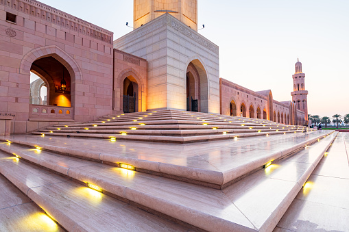 The Sultan Qaboos Grand Mosque low angle view with shiny steps in the foreground in the golden hour, Muscat, Oman