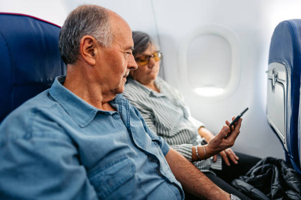 istock Senior Couple Using Smart Phone In An Airplane 2010188767
