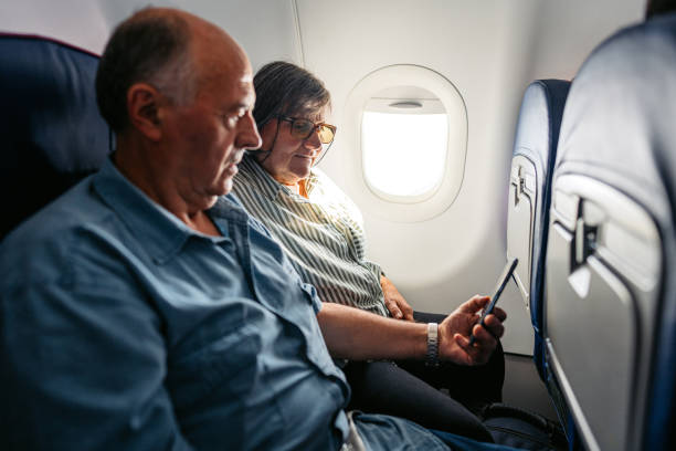 istock Senior Couple Using Smart Phone In An Airplane 2010189877