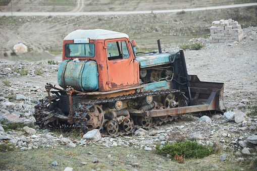 An old vintage tractor on a farm. Non-working condition, rust.