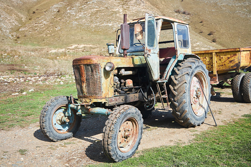 An old vintage tractor on a farm. Non-working condition, rust.