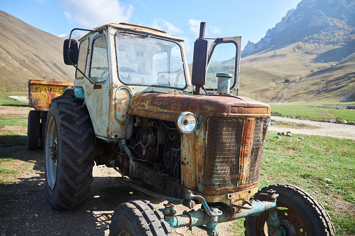 An old vintage tractor on a farm. Non-working condition, rust.