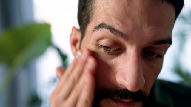 Man applying a cream on his face during his facial treatment routine
