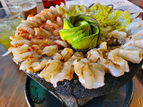 Savory shrimp molcajete dish artfully presented with fresh avocado, captured in a casual dining setting