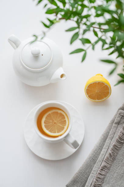 istock A cup of tea with lemon, a teapot and green branch on a white table. 2010230631
