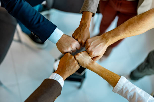 istock Coworkers joining hands in the office 2010237470