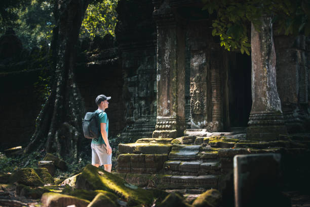 Traveler with backpack admiring ancient temple in Cambodia