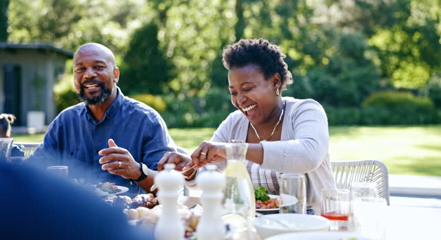 Family, eating and lunch in garden for happy at thanksgiving with bonding, care or love for celebration. Black people, patio and brunch at table for party, event or conversation for holiday or diet