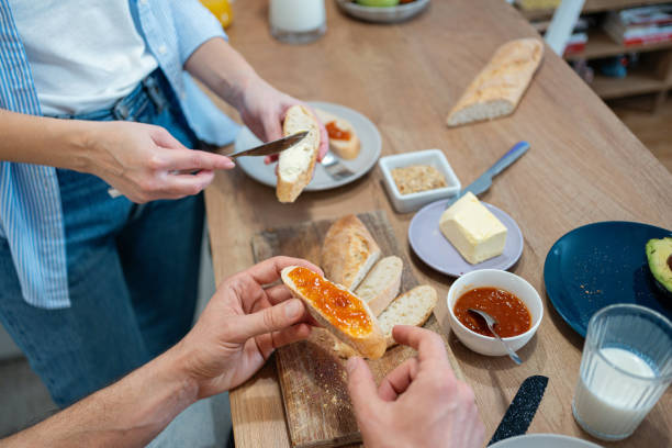 istock Unrecognizable couple having butter and jam on toasted bread for breakfast in the kitchen 2010255360