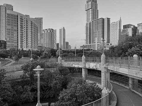 In this monochrome photo, the cityscape of Austin, Texas, is captured from the vantage point of a pedestrian bridge.