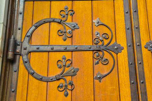 Turquoise colored metal ornaments on a brown wooden church door.